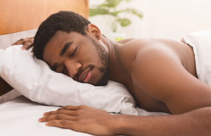 A stomach sleeper hugging a flat memory foam pillow, showing relaxed shoulders.