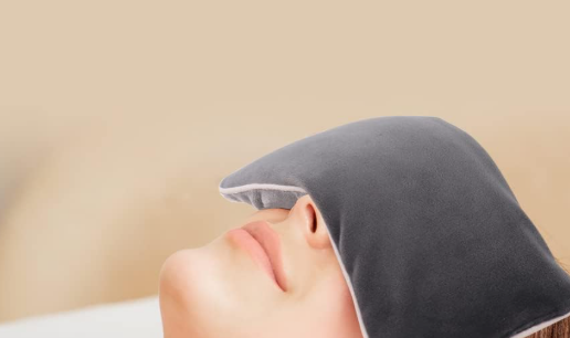 A woman resting peacefully in bed while wearing a comfortable weighted sleep mask that blocks out light.