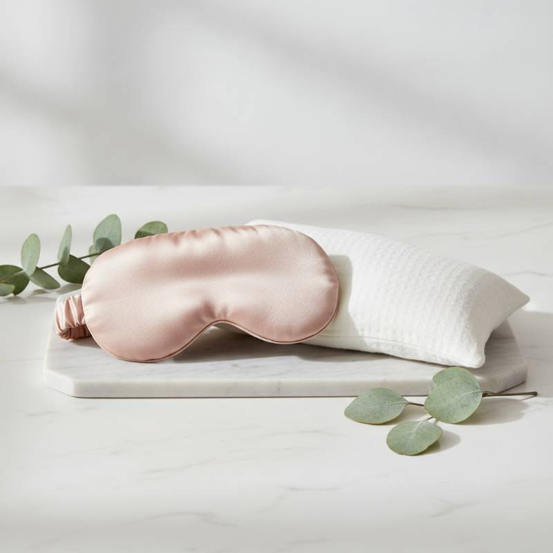 A high-end lifestyle shot comparing a silk weighted sleep mask and a cotton lavender eye pillow.