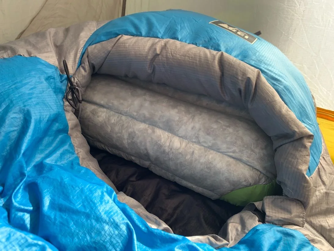 Down-topped camping pillow positioned inside a sleeping-bag hood
