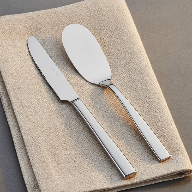 A table knife next to a smooth butter spreader on a napkin.